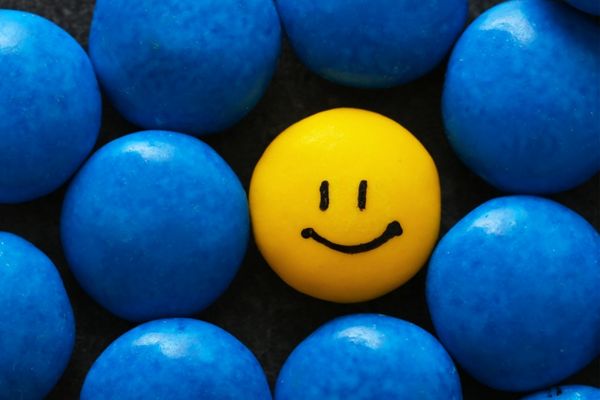 Geel smiley bolletje tussen blauwe bolletjes